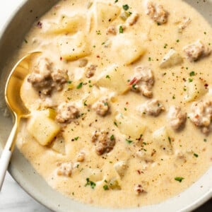a bowl of creamy sausage and potato soup with a spoon