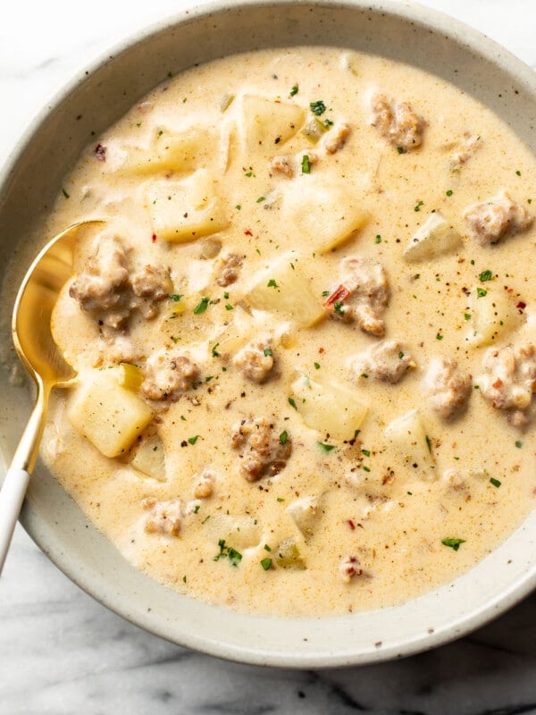 a bowl of creamy sausage and potato soup with a spoon