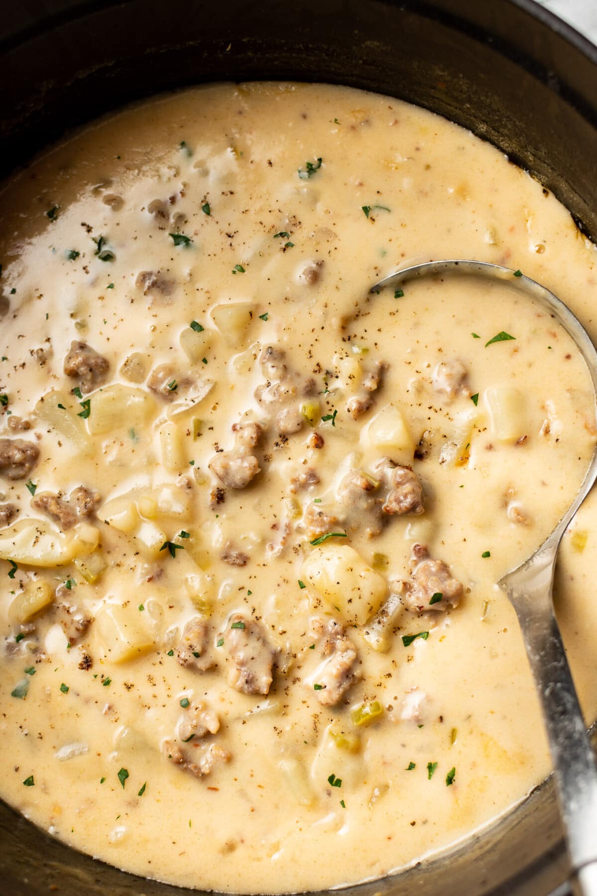 a pot of creamy sausage potato soup with a ladle