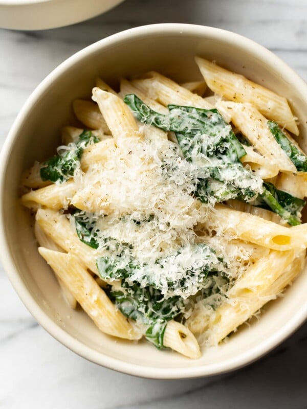 close-up of creamy spinach pasta in a beige bowl