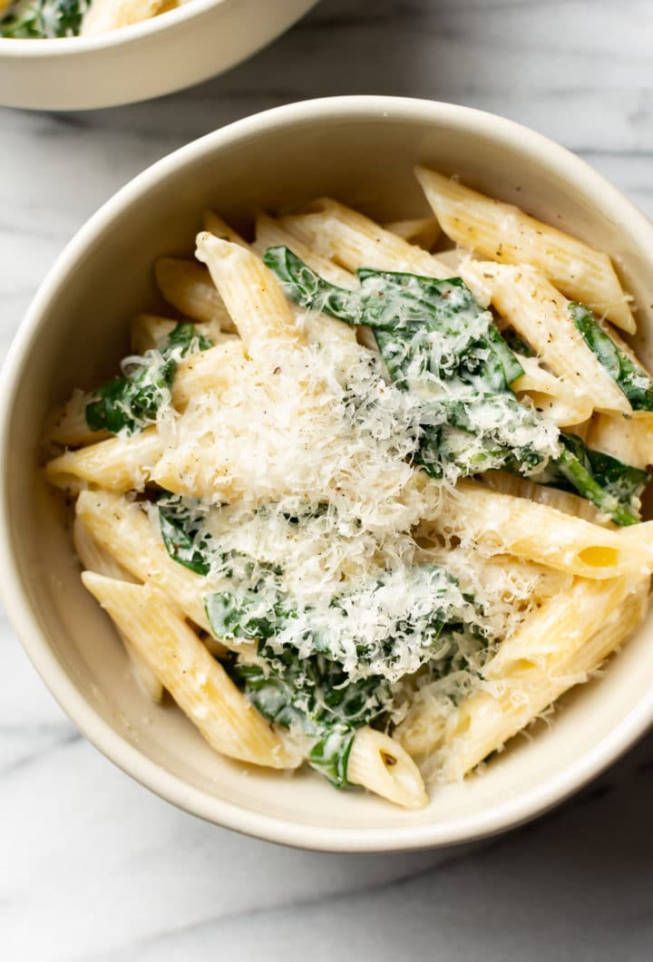 close-up of creamy spinach pasta in a beige bowl