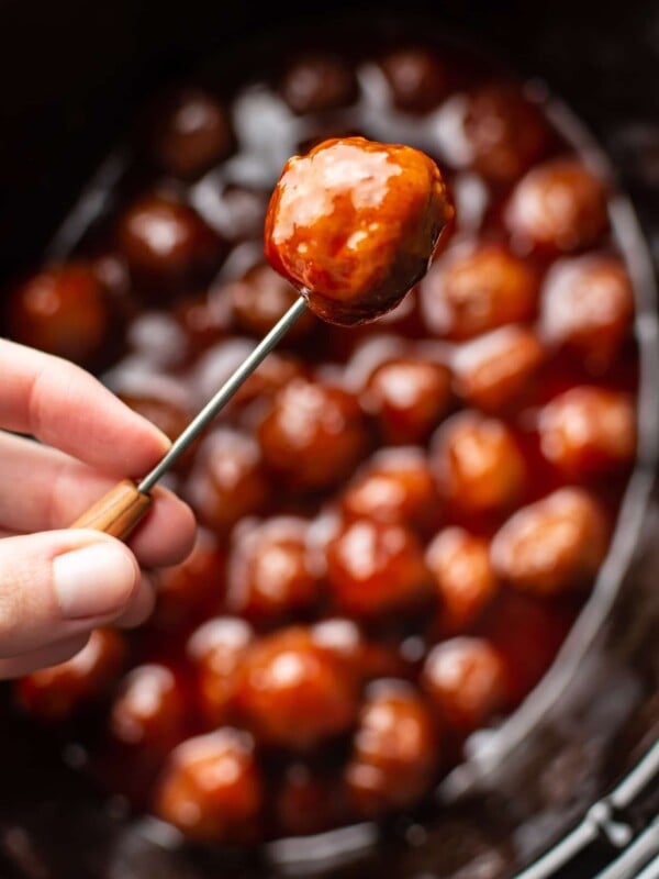 grape jelly meatball being held up on a cocktail toothpick