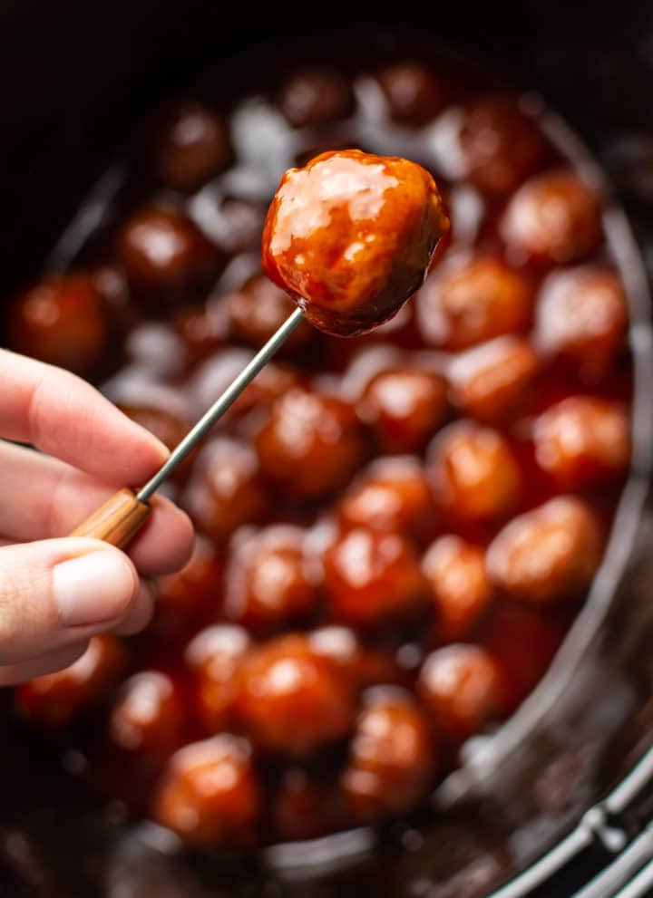 grape jelly meatball being held up on a cocktail toothpick
