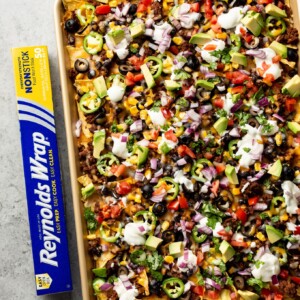 loaded sheet pan nachos topped to perfection with sour cream, fresh tomatoes, avocado, etc.