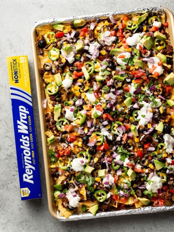 loaded sheet pan nachos topped to perfection with sour cream, fresh tomatoes, avocado, etc.