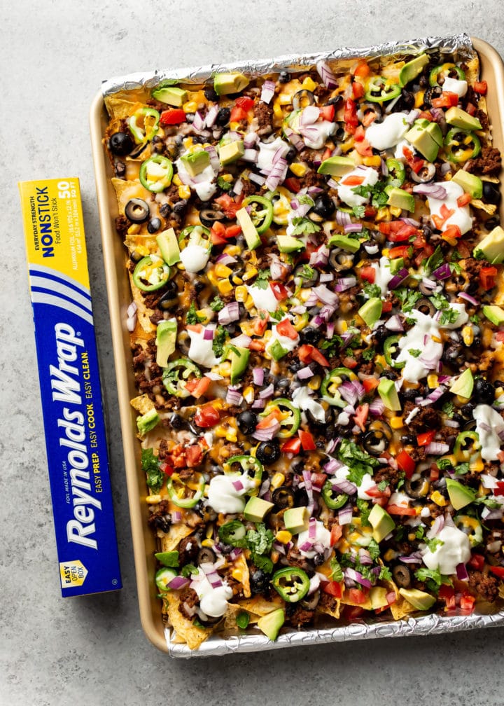 loaded sheet pan nachos topped to perfection with sour cream, fresh tomatoes, avocado, etc.