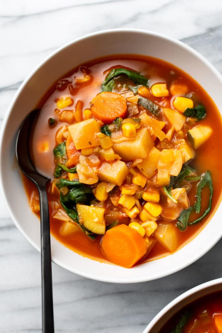 cabbage vegetable soup in a white bowl with a spoon