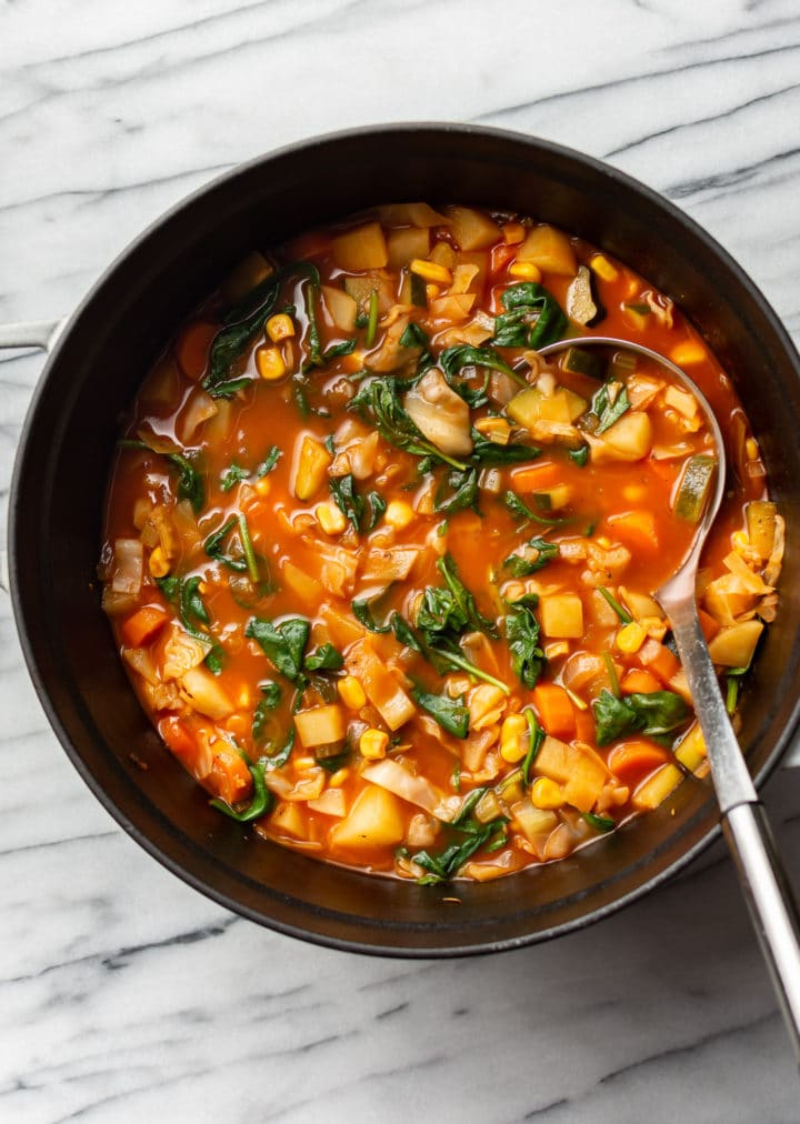 cabbage soup with vegetables in a pot with a ladle