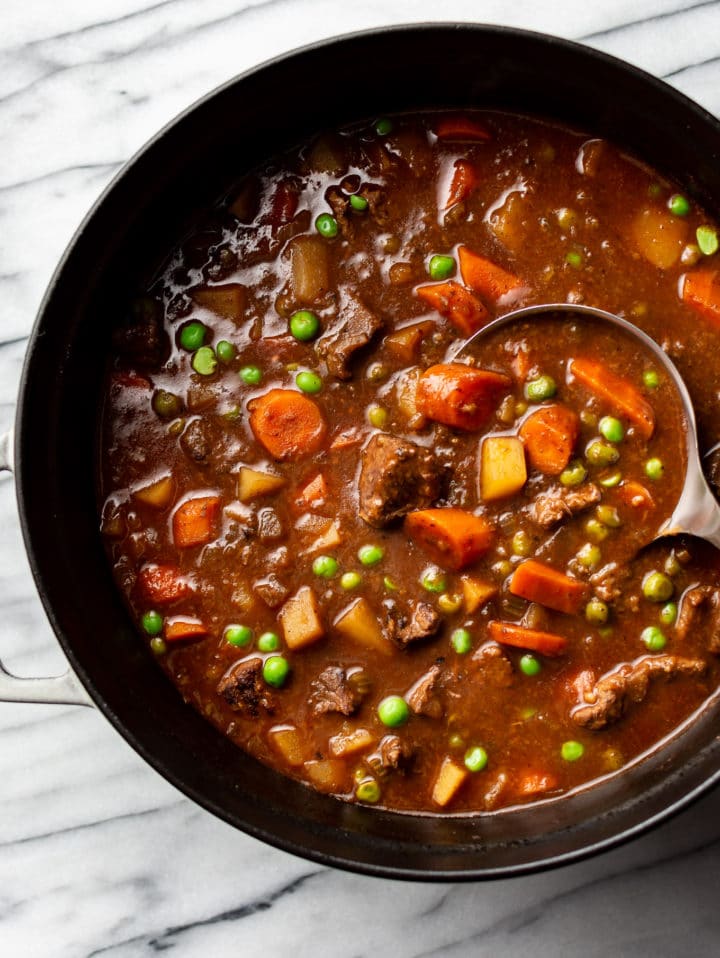 close-up of best beef stew in a Dutch oven with a ladle in the pot