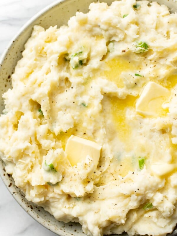 mashed potatoes with sour cream close-up in a serving bowl with butter pats on top