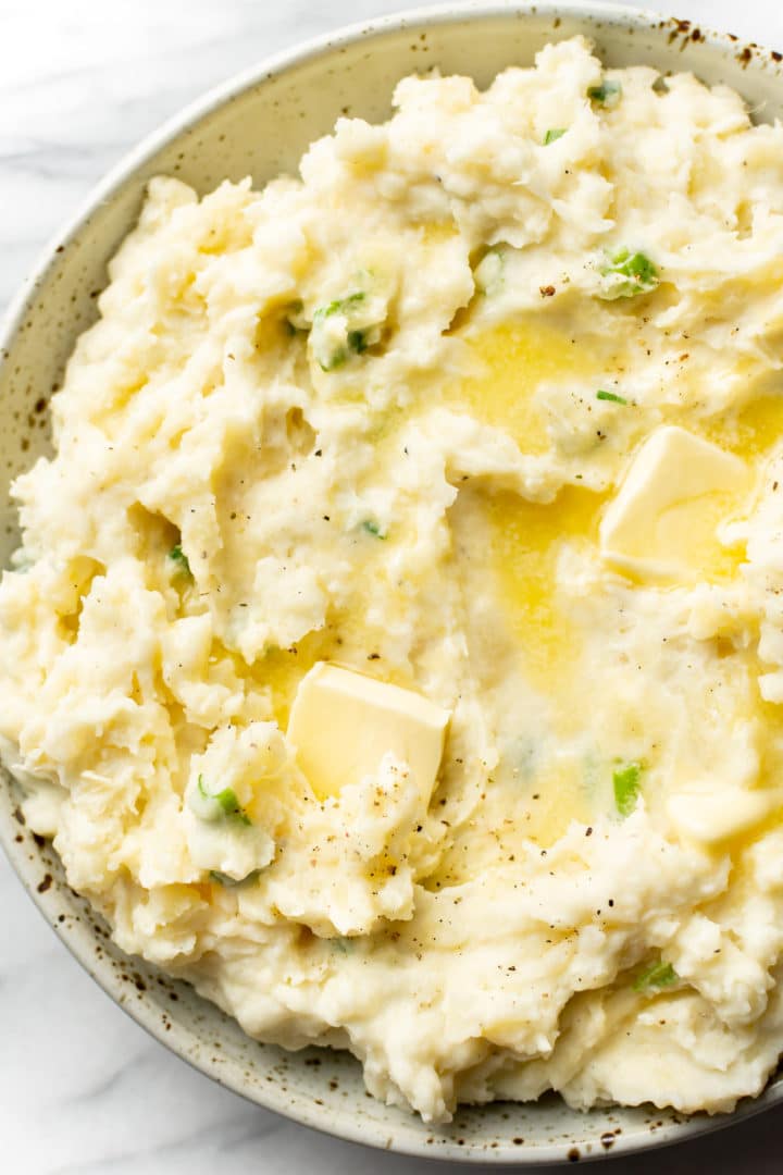 mashed potatoes with sour cream close-up in a serving bowl with butter pats on top