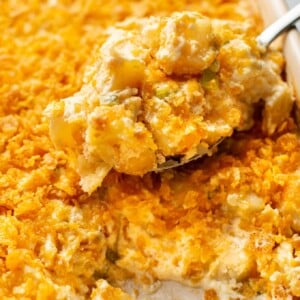 close-up of a spoonful of funeral potatoes being lifted from a casserole dish