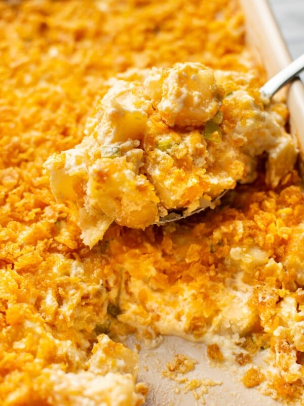 close-up of a spoonful of funeral potatoes being lifted from a casserole dish
