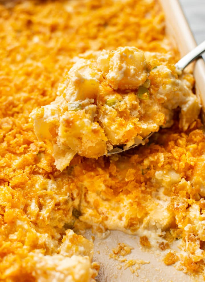 close-up of a spoonful of funeral potatoes being lifted from a casserole dish