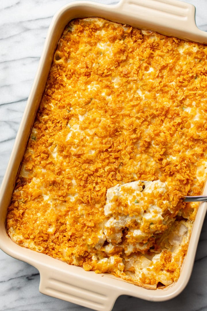 a baking dish with cheesy funeral potatoes and a serving spoon