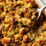 close-up of a spoonful of sausage stuffing in a casserole dish