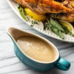 homemade turkey gravy in blue gravy boat with a roasted turkey in the background