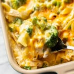 close-up of a serving spoon taking a large spoonful of chicken noodle casserole from the baking dish