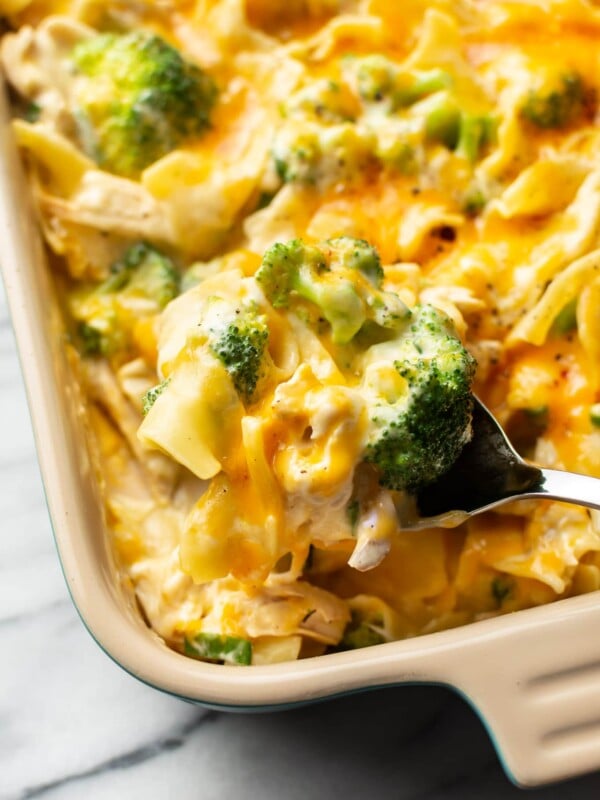 close-up of a serving spoon taking a large spoonful of chicken noodle casserole from the baking dish