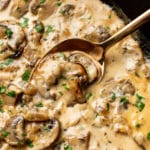 extreme close-up of creamy mushroom sauce in a cast iron skillet with a serving spoon