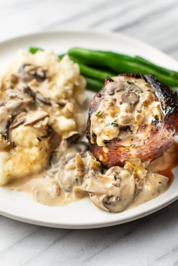close-up of a plate with a steak, mashed potatoes, and green beans in a mushroom cream sauce