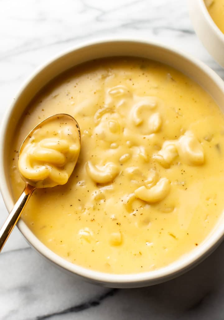 a bowl of macaroni and cheese soup with a spoon