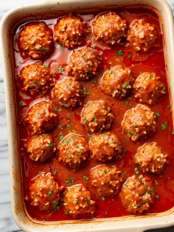 baking dish on marble surface with several porcupine meatballs in sauce