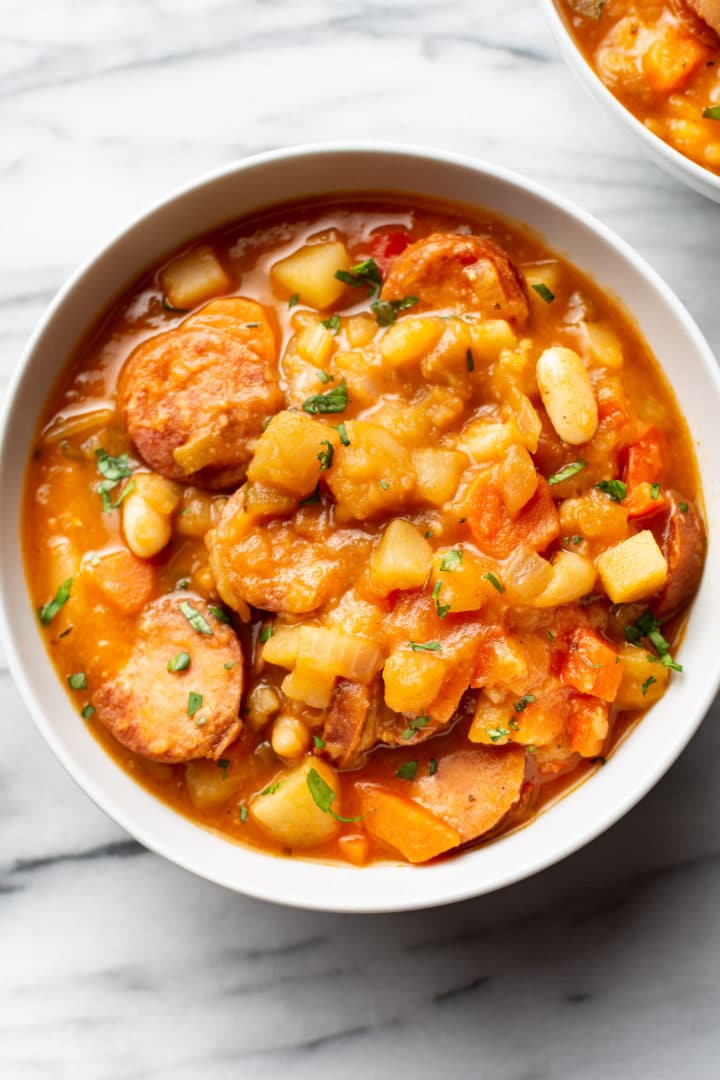 close-up of a bowl of homemade sausage stew on a marble surface