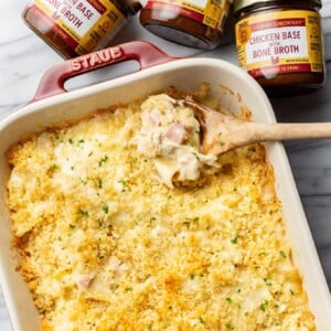 a baking dish with chicken cordon bleu casserole, a wooden spoon, and three jars of zoup concentrate