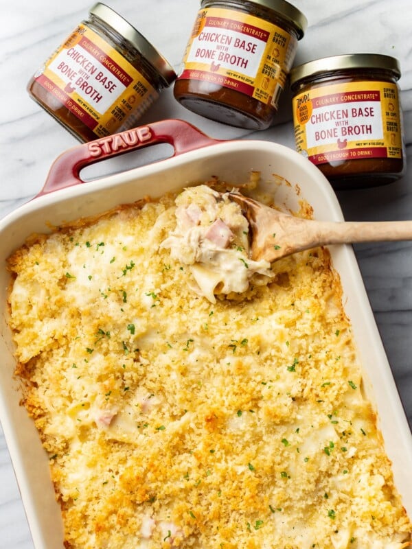 a baking dish with chicken cordon bleu casserole, a wooden spoon, and three jars of zoup concentrate