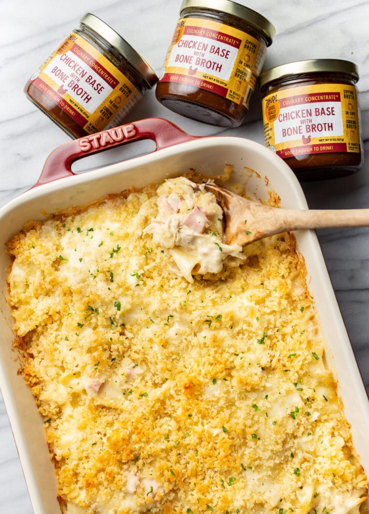 a baking dish with chicken cordon bleu casserole, a wooden spoon, and three jars of zoup concentrate