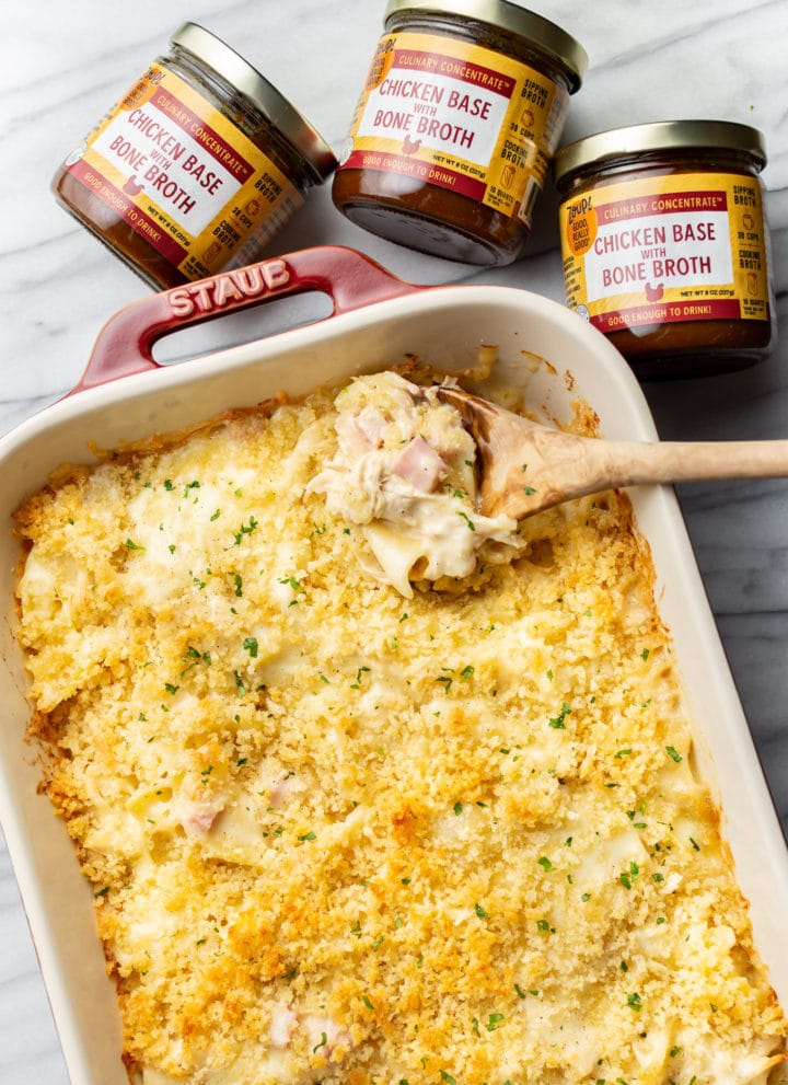 a baking dish with chicken cordon bleu casserole, a wooden spoon, and three jars of zoup concentrate