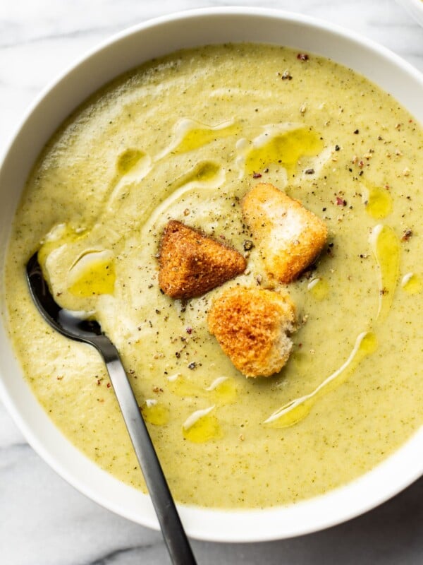 a bowl of cream of broccoli soup with croutons and a spoon
