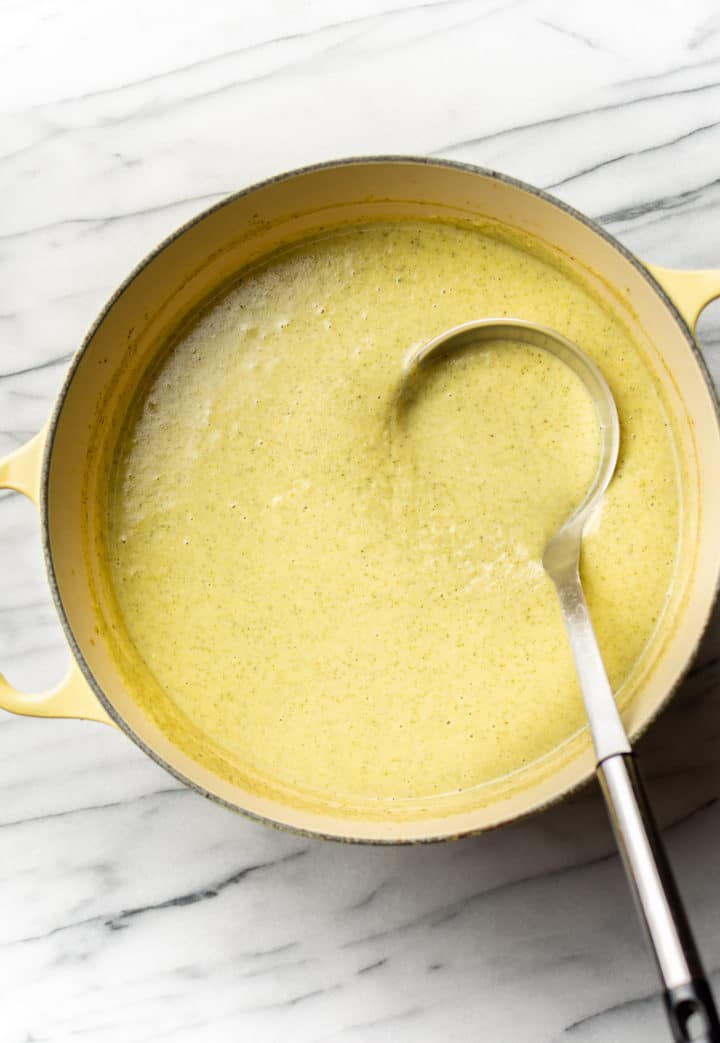 a pot of cream of broccoli soup with a ladle