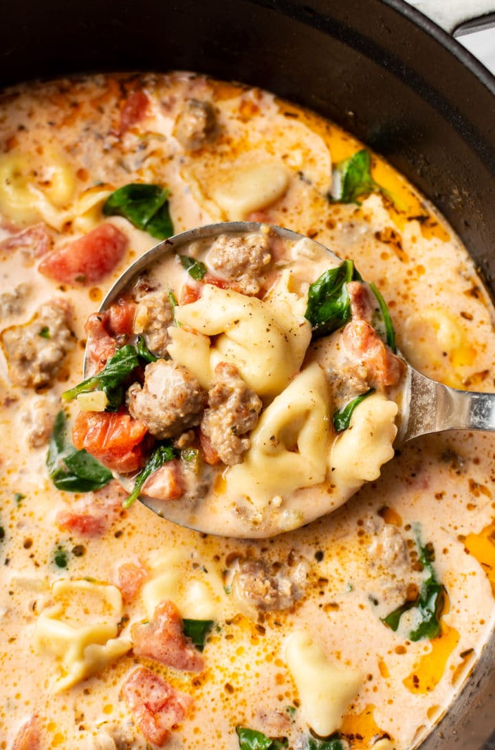 close-up of a ladle in a soup pot with creamy italian sausage tortellini soup