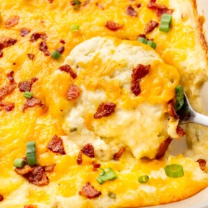 close-up of a serving spoon in a baking dish with loaded mashed potato casserole