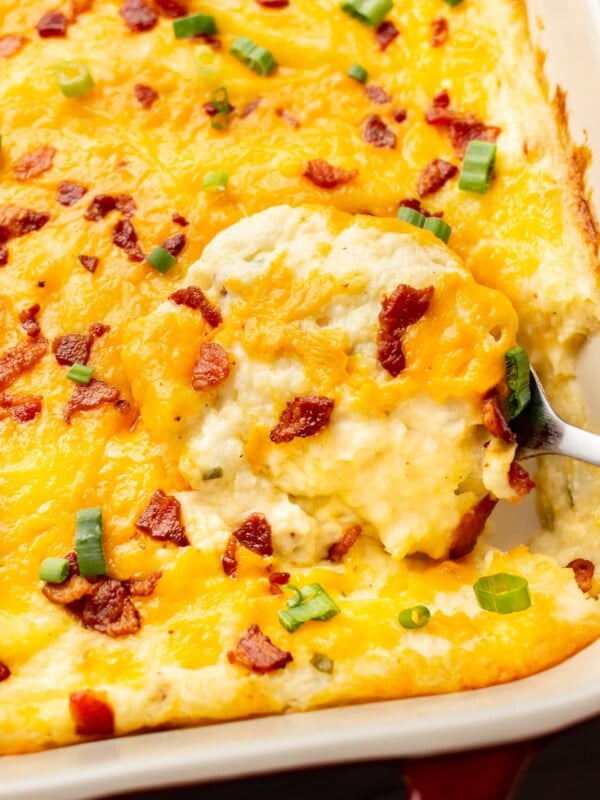 close-up of a serving spoon in a baking dish with loaded mashed potato casserole