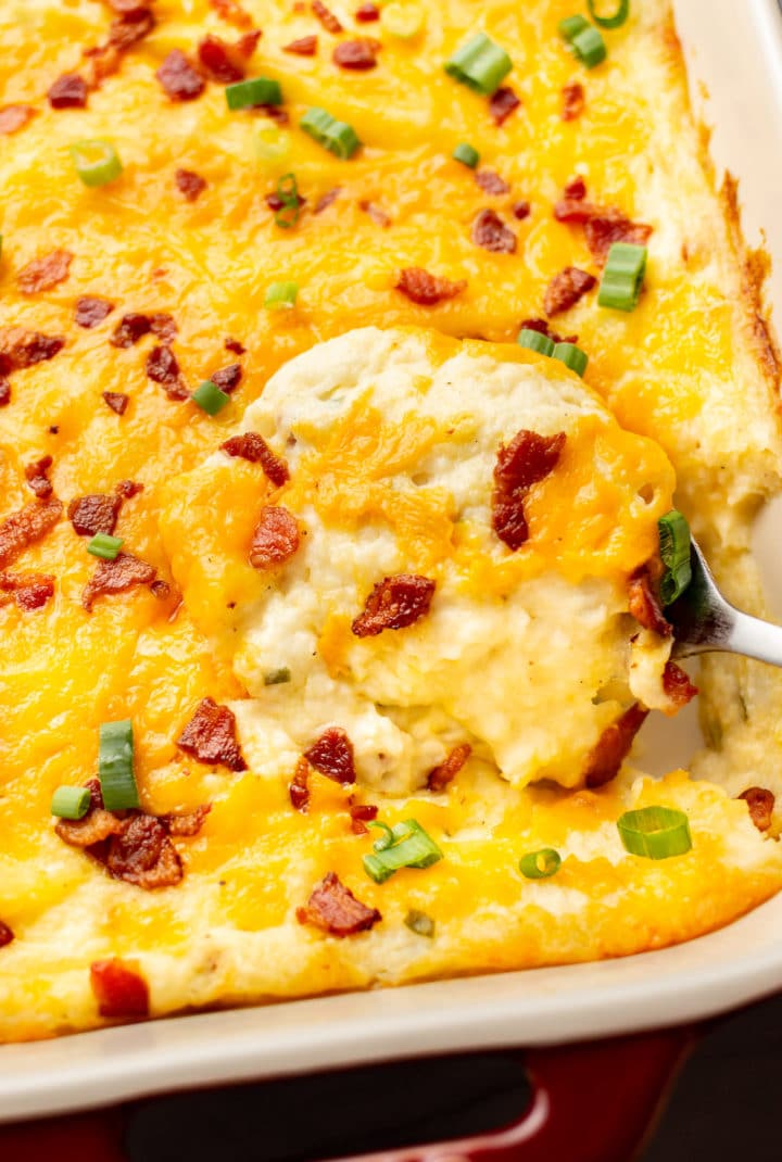 close-up of a serving spoon in a baking dish with loaded mashed potato casserole