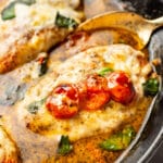 close-up of a spoon serving a portion of pesto chicken from a cast iron skillet