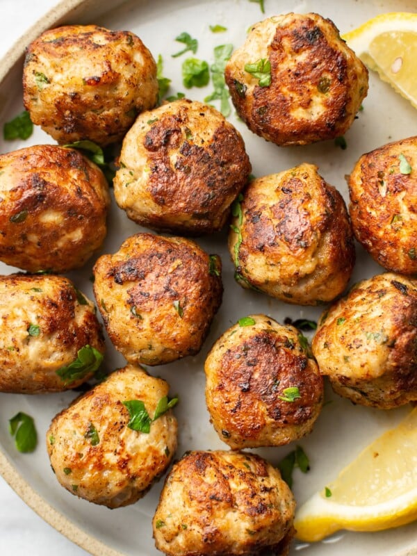 close-up of several ground turkey meatballs on a plate with lemon wedges