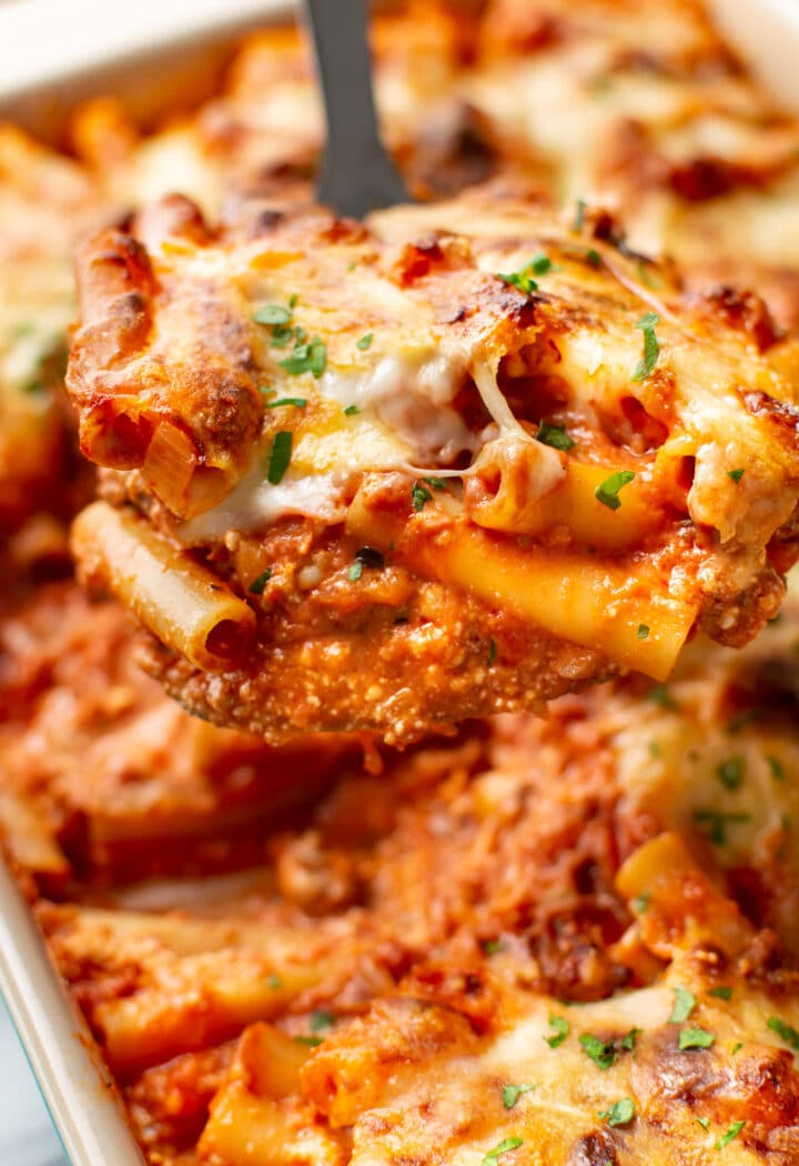 close-up of a metal spatula with a serving of cheesy baked ziti