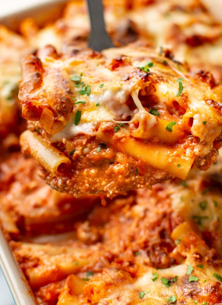 close-up of a metal spatula with a serving of cheesy baked ziti