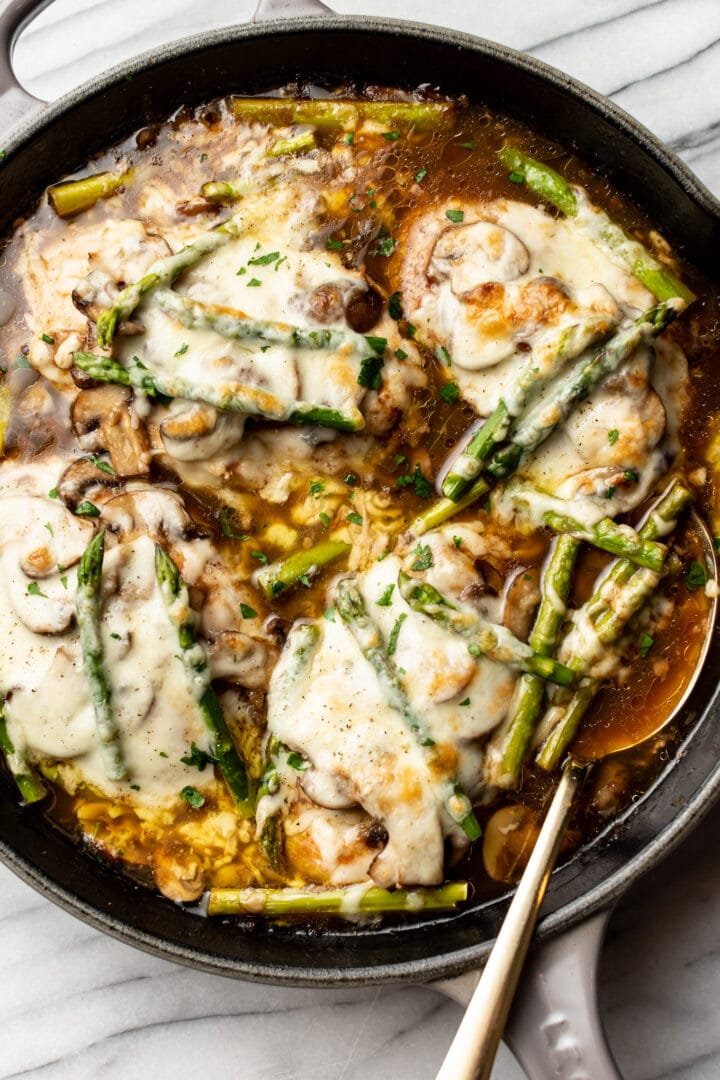 a cast iron skillet with chicken madeira and a serving spoon