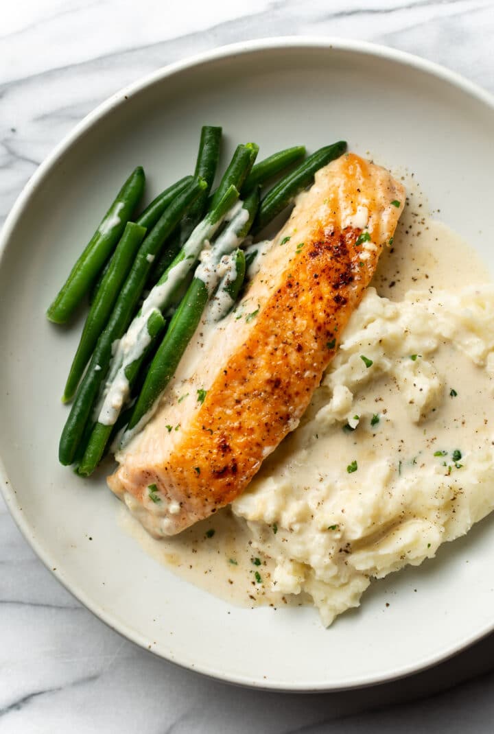 a plate with creamy garlic salmon, mashed potatoes, and green beans