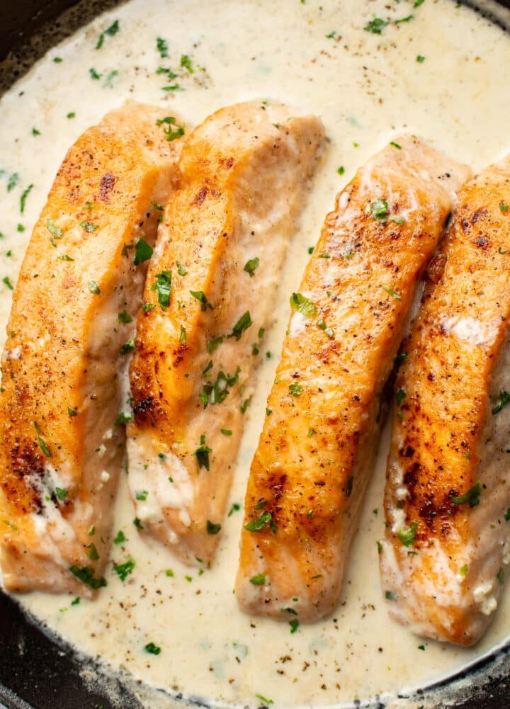 closeup of four pieces of creamy garlic salmon in a skillet