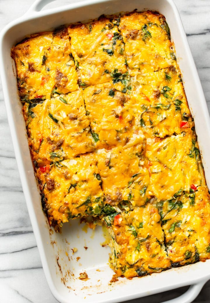 a casserole dish with sausage breakfast casserole with a piece removed