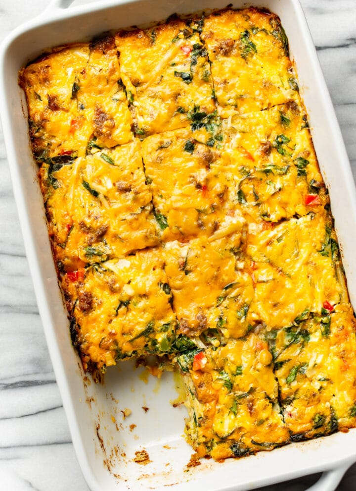 a casserole dish with sausage breakfast casserole with a piece removed