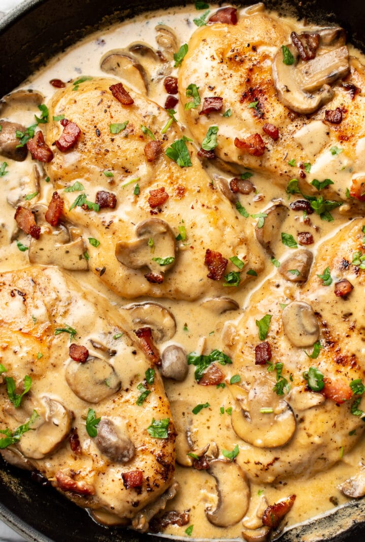 a cast iron skillet with chicken in a bacon cream sauce