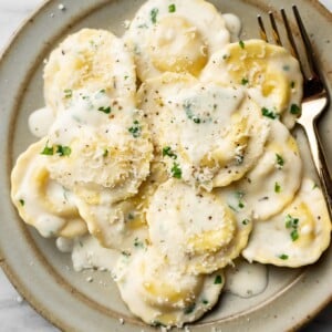 a bowl of ravioli in cream sauce with a fork