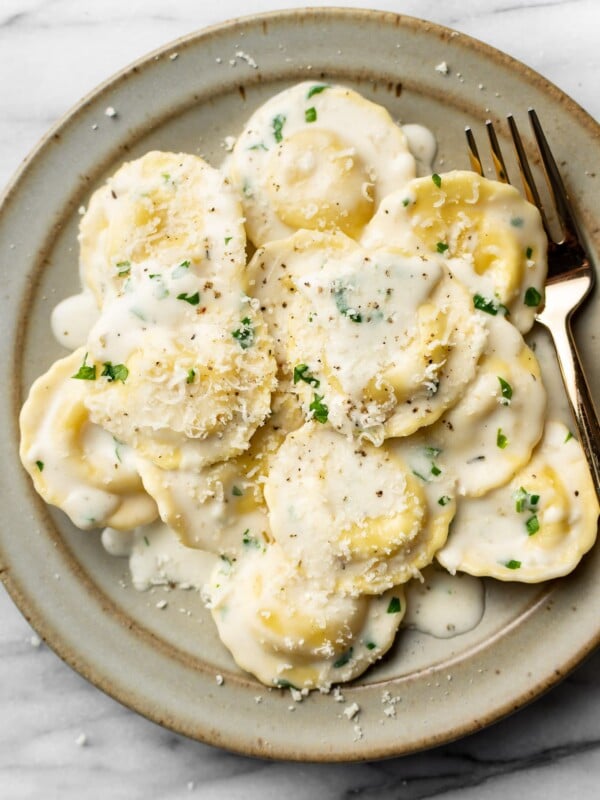 a bowl of ravioli in cream sauce with a fork